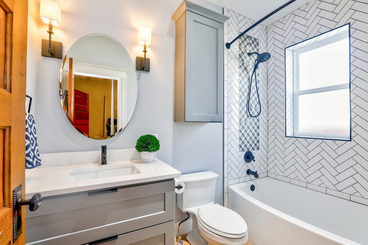 gallery-4 Elegant modern bathroom featuring chevron tiles, oval mirror, and sleek fixtures for a contemporary look.