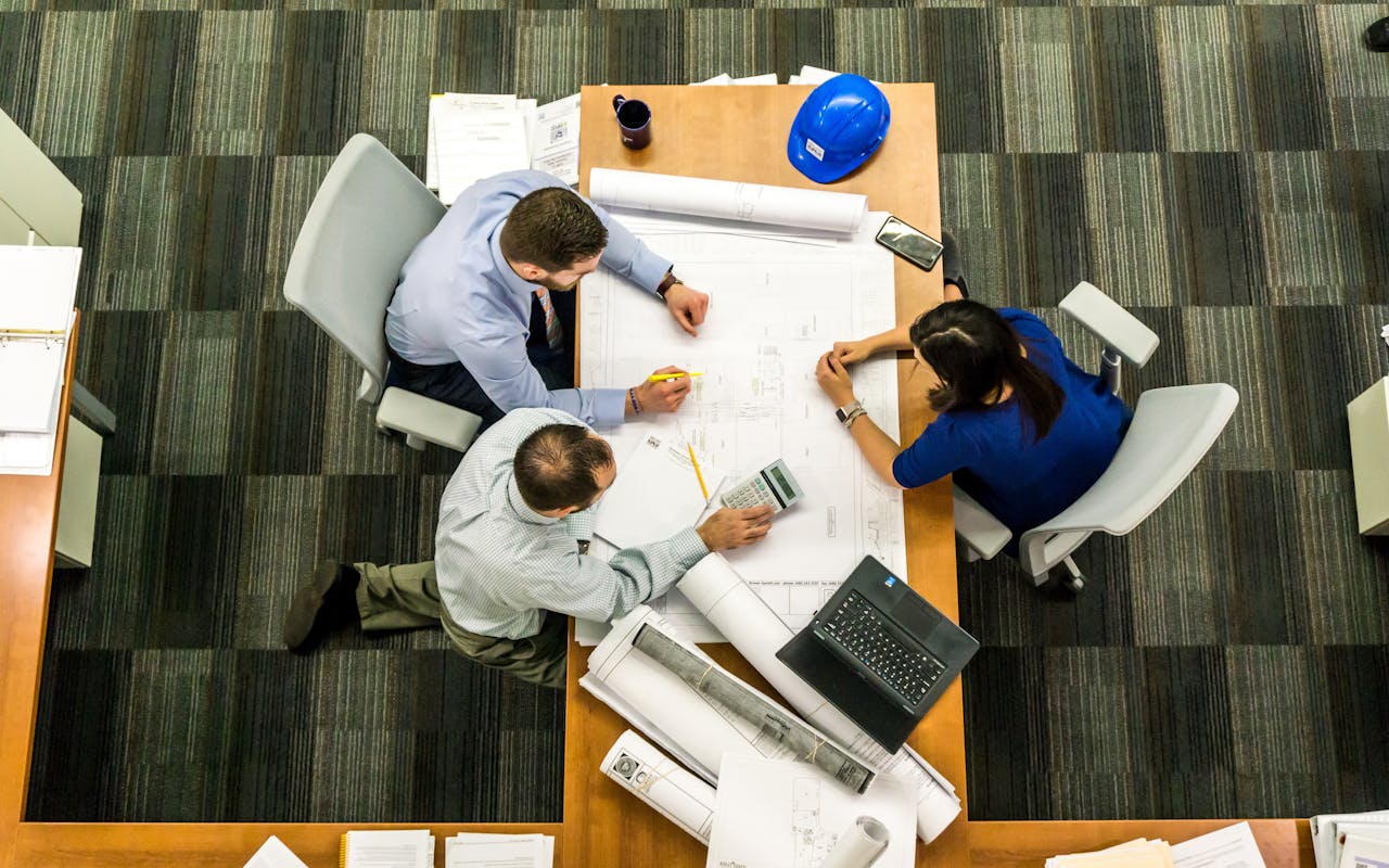 about-01 Top view of a team working on construction plans in an office setting.